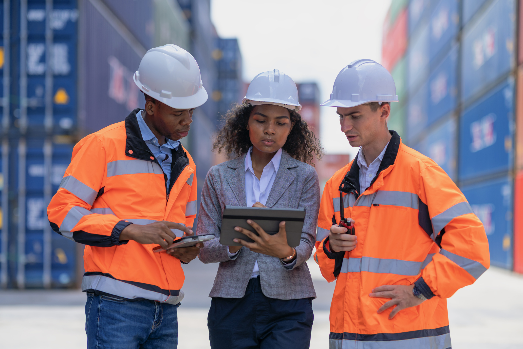 Logistic engineers and businesswomen are managed and confirm shipment on a digital tablet They are discussing the loading and unloading of cargo containers and trucks, including coordinating with crane operators at the cargo container yard.