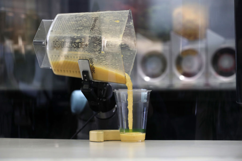 Smoothie pouring out of blender into cup