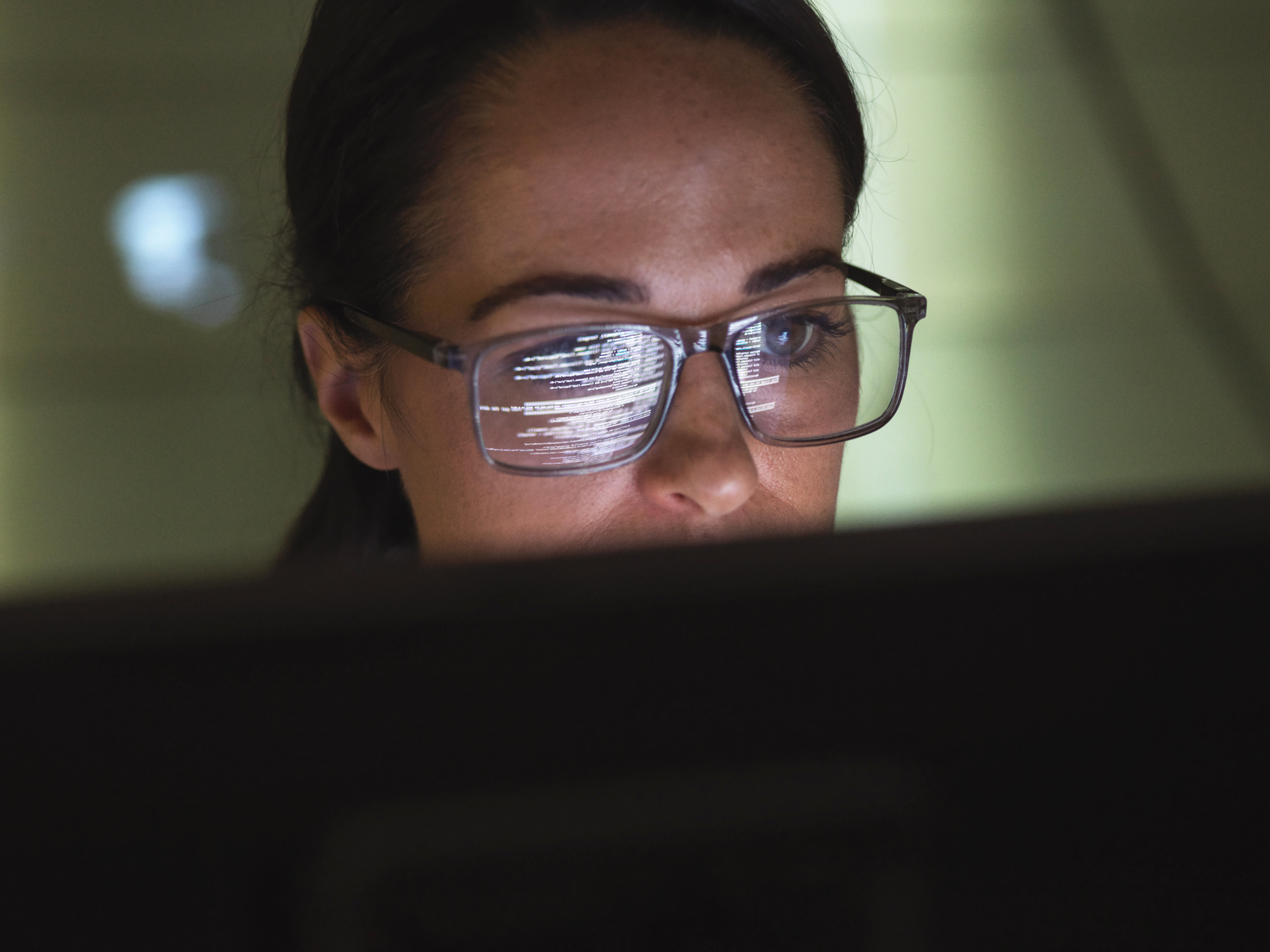 Close-up of a female computer programmer writing code on her desktop computer at work.