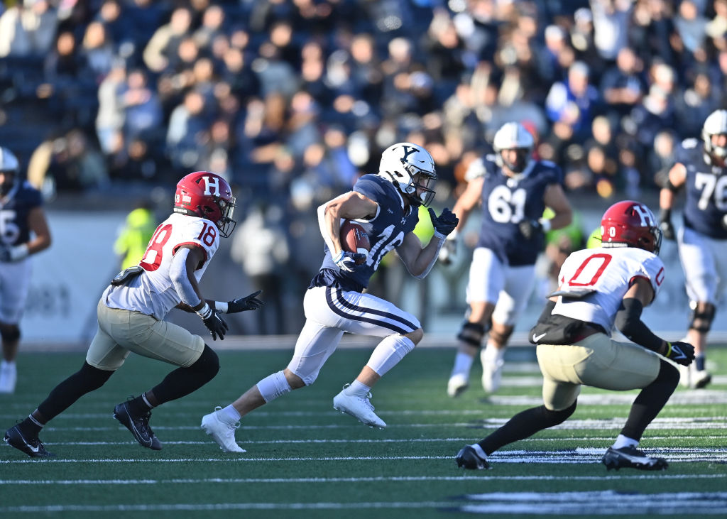 Football players on a field during a Harvard vs Yale game