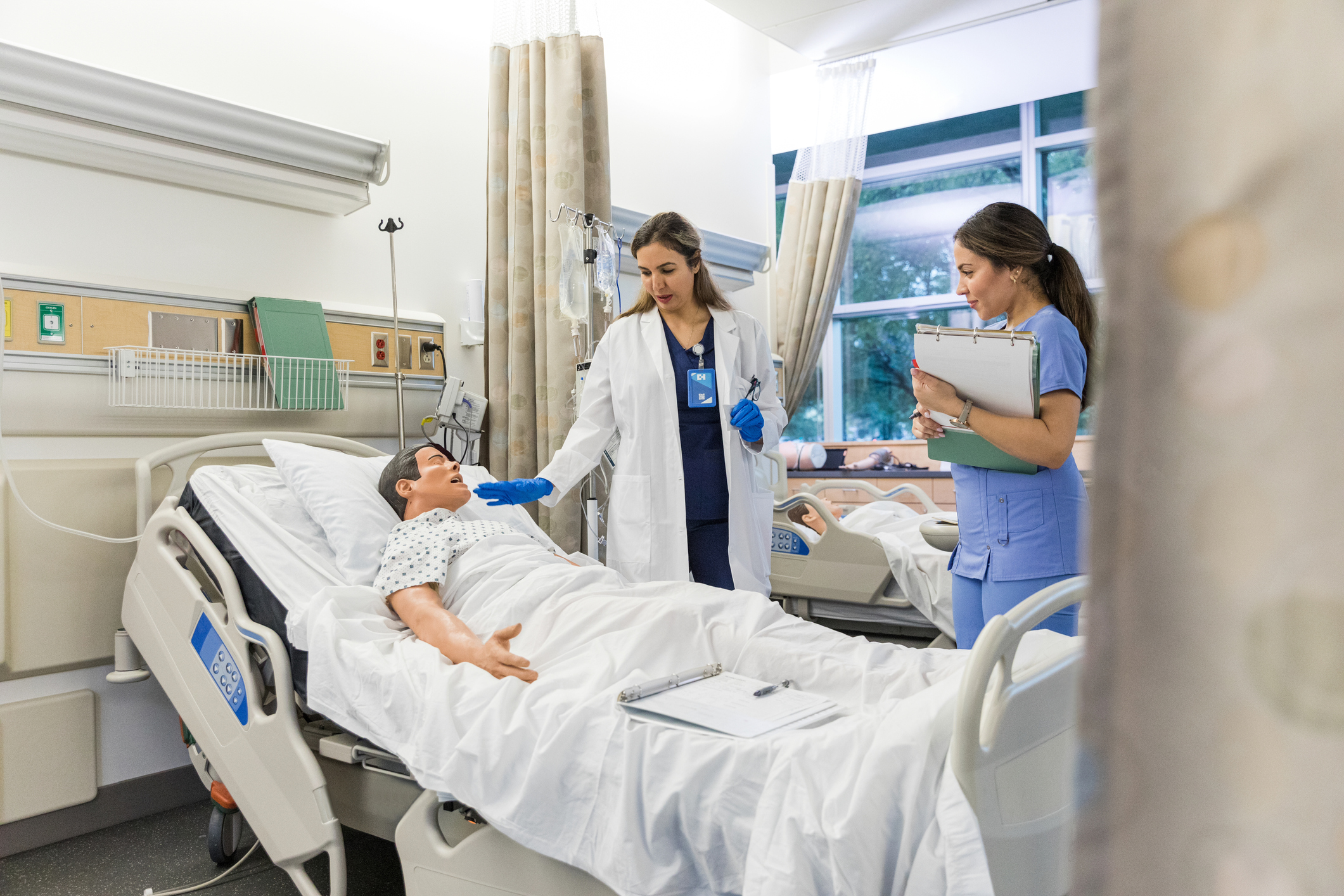 Nurses practicing on CPR dummy in hospital bed